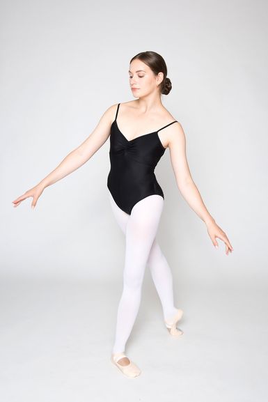 Eine Frau in einem schwarzen Trikot und weißen Strumpfhosen posiert in einer Ballettposition.