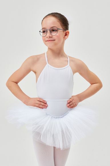 Ein junges Mädchen in weißem Ballett-Tutu steht mit den Händen in den Hüften.
