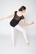 Eine Balletttänzerin in einem schwarzen Trikot und weißen Strumpfhosen posiert auf Spitze vor einem schlichten