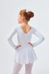 Ein junges Mädchen in einem weißen Ballett-Outfit steht mit den Händen in den Hüften und blickt von der Kamera weg. 2