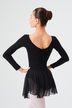Eine Balletttänzerin in einem schwarzen Ballettbody und Rock posiert mit den Händen in den Hüften und blickt von der Kamera weg. 2