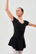 Eine junge Balletttänzerin in einem schwarzen Ballettbody und Strumpfhosen posiert mit erhobenen Armen. 1