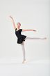 Eine Balletttänzerin in einem schwarzen Ballettbody und weißen Strumpfhosen führt eine Arabeskenpose aus. 3