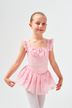 Junges Mädchen in einem rosa Ballettkleid und weißen Strumpfhosen posiert mit einem leichten Lächeln. 1