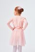 Ein junges Mädchen in einem rosa Ballett-Outfit steht mit den Händen in den Hüften und blickt von der Kamera weg. 2