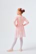 Ein junges Mädchen in einem rosa Ballett-Outfit und Strumpfhosen steht mit den Händen in den Hüften und blickt von der Kamera weg. 4