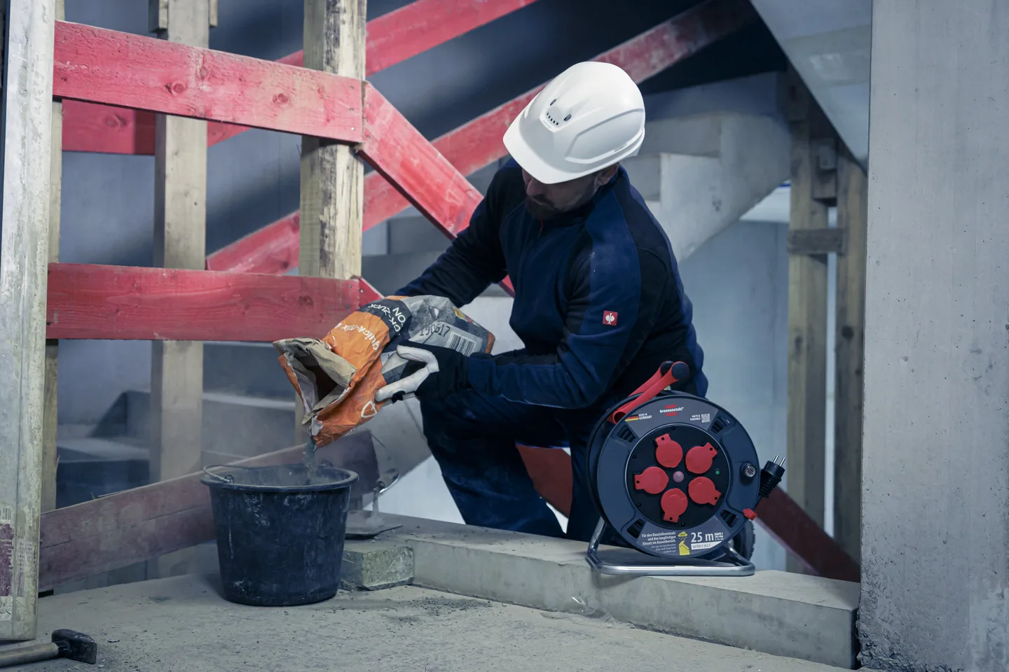 Brennenstuhl Professional Kabeltrommel auf der Baustelle, im Hintergrund arbeitet ein Handwerker mit einem Winkelschleifer