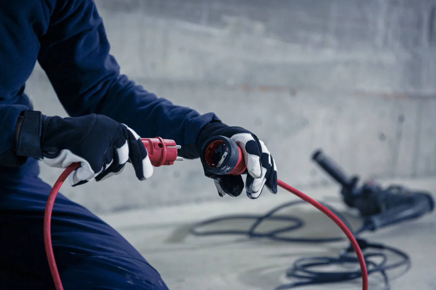 Handwerker verbindet ein rotes Brennenstuhl Professional Verlängerungskabel BREMAXX-PUR mit einem Winkelschleifer