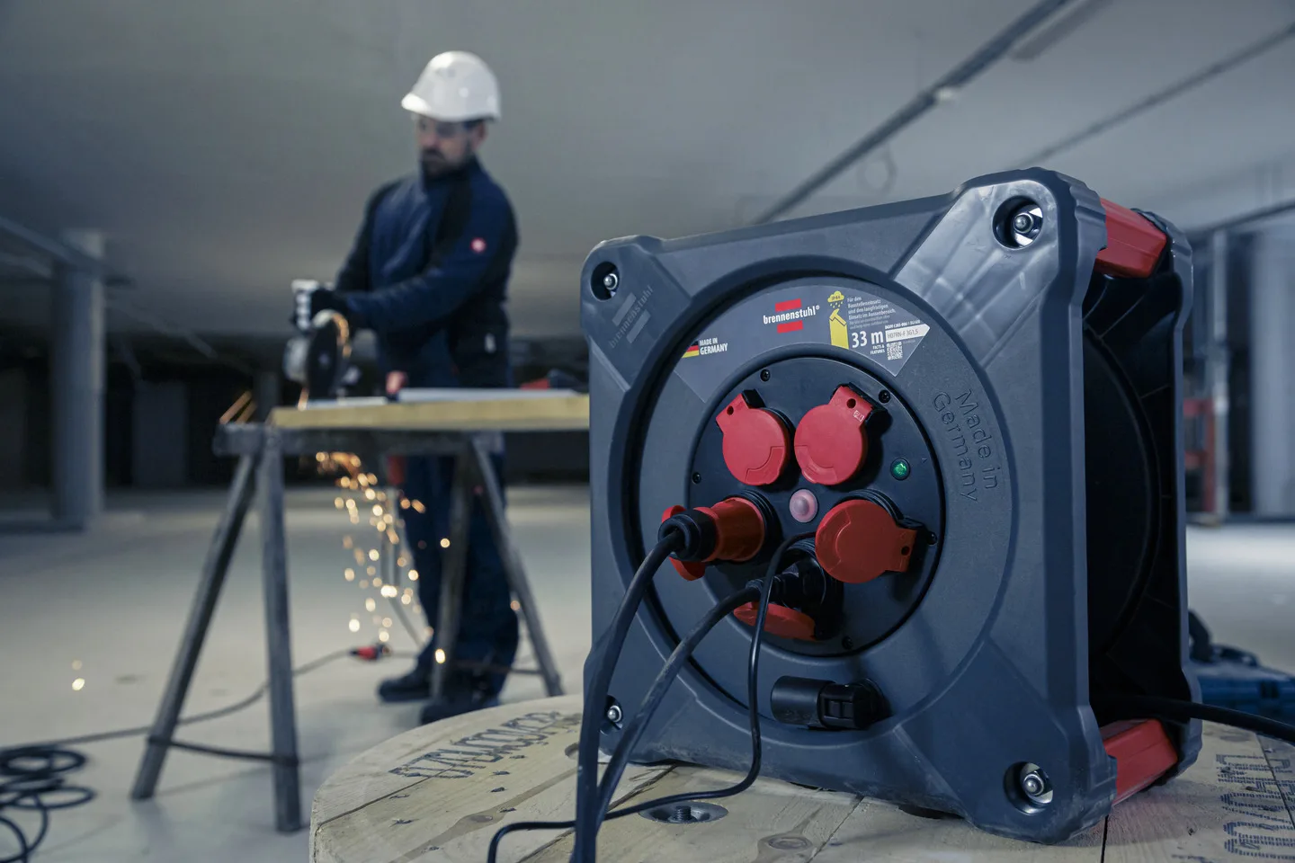 Handwerker arbeitet mit einem Winkelschleifer, daneben steht eine Brennenstuhl Professional Baustellen-Kabeltrommel KA