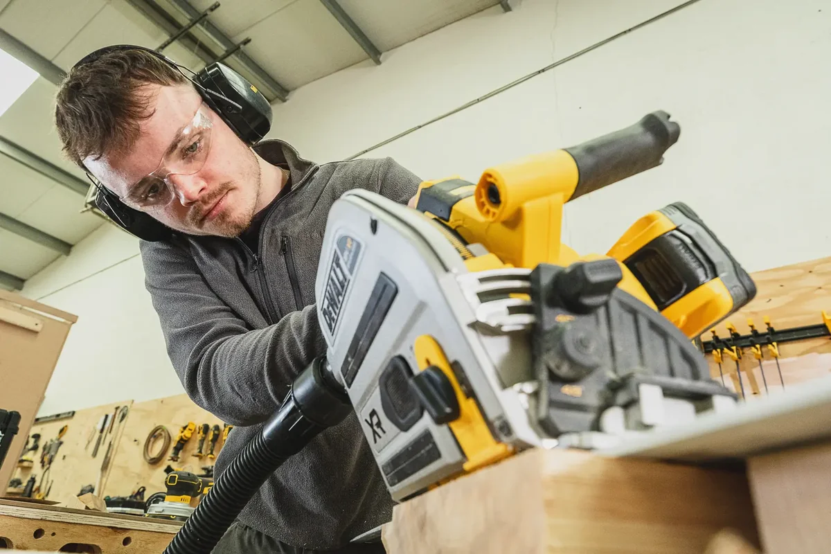 Handwerker setzt die DEWALT DCS525 auf der Führungsschiene an der Plattenkante an