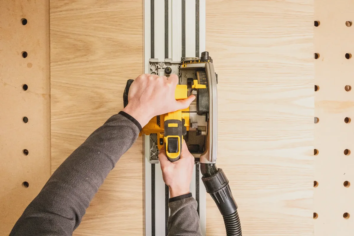 DEWALT DCS525 von oben auf der Führungsschiene beim Schnitt durch eine furnierte Platte