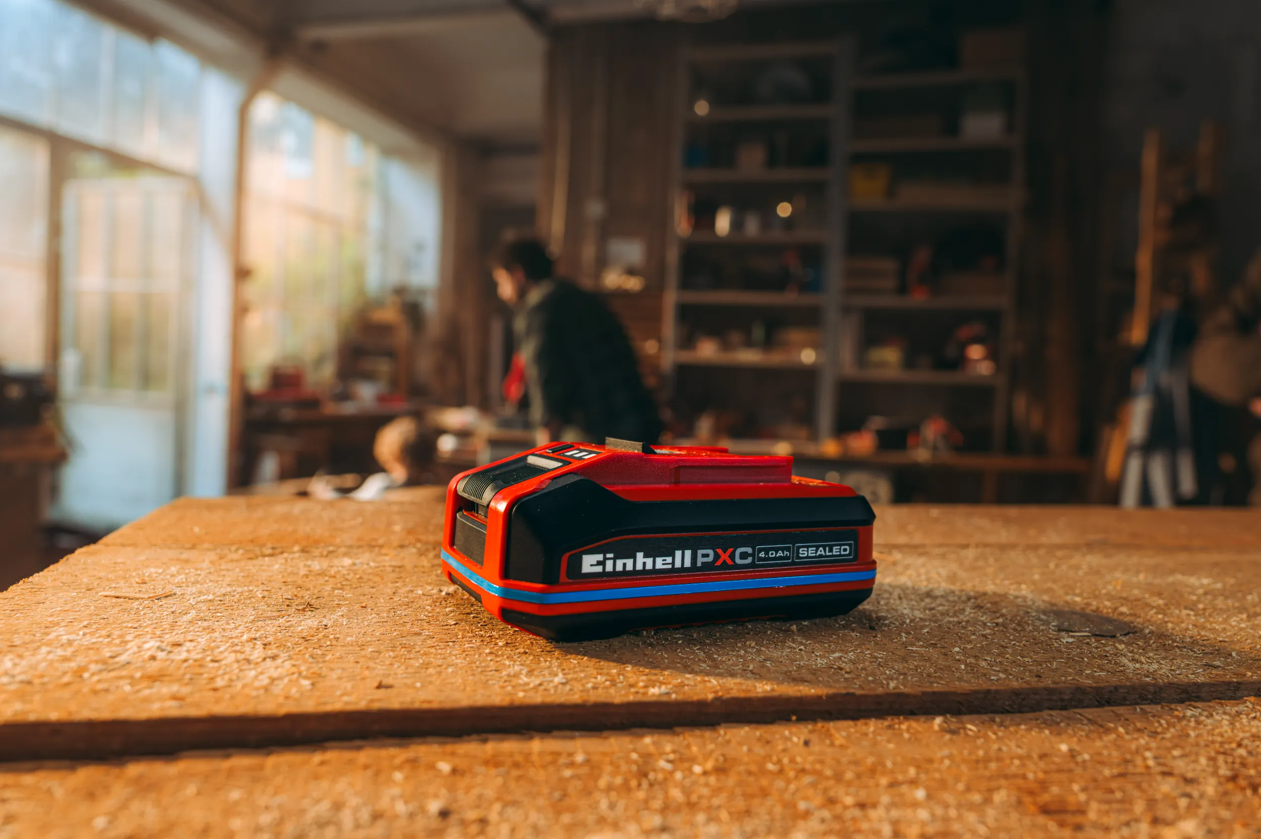 Einhell SEALED Akku auf einer Werkbank mit Sägestaub.