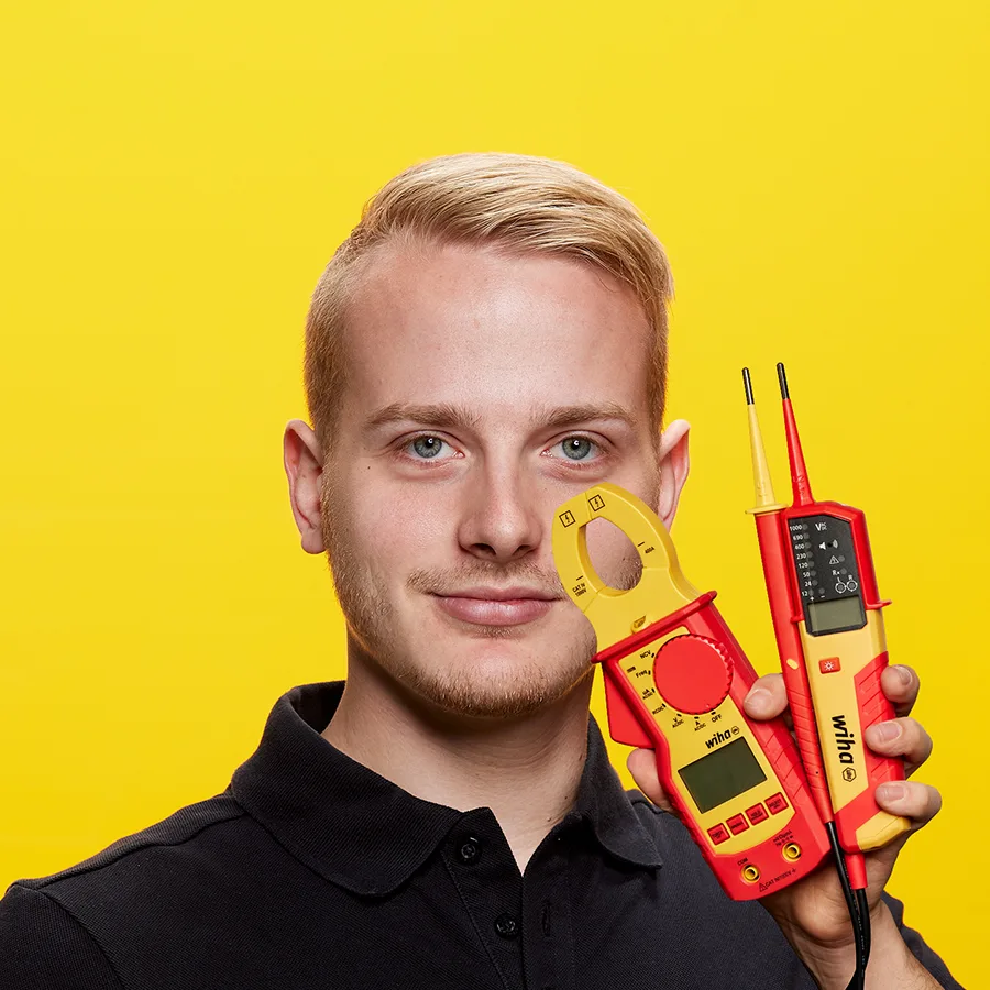 Elektriker hält eine Wiha Strommesszange und einen zweipoligen Wiha Spannungsprüfer in der Hand