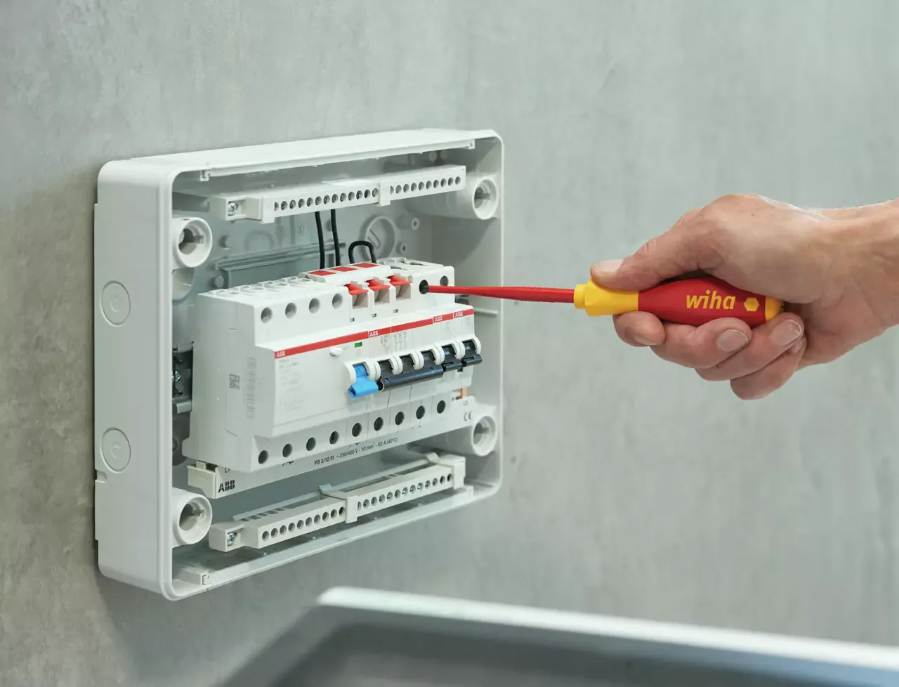 Elektriker arbeitet mit einem isolierten Wiha VDE-Schraubendreher an einem Sicherungsverteiler