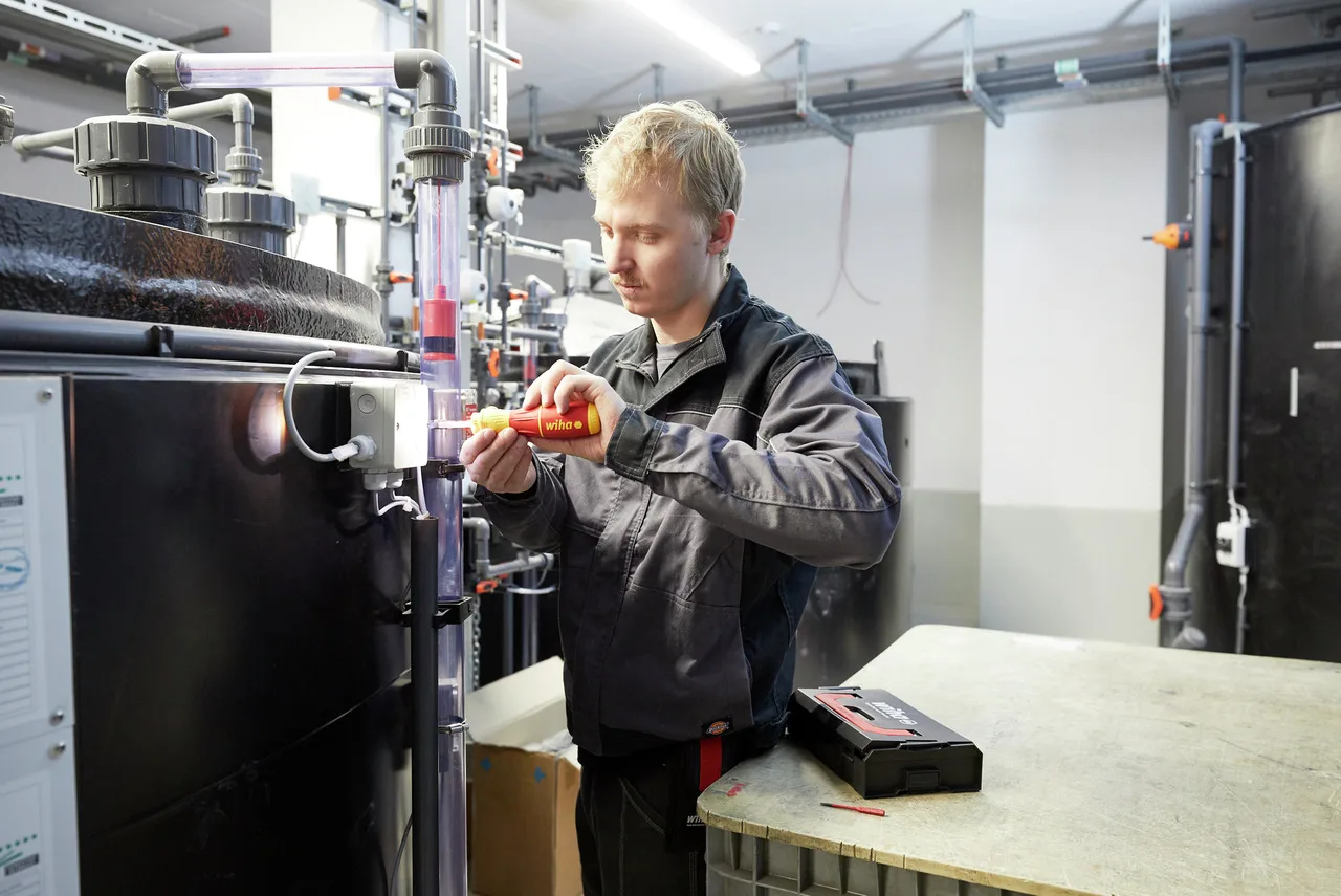 Elektriker arbeitet mit einem isolierten Wiha E-Schraubendreher an einer Anlage in einer Industriehalle