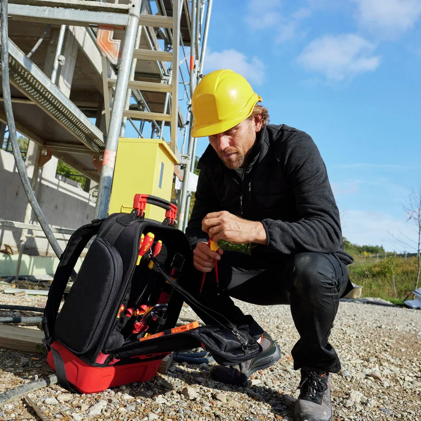 Elektriker nimmt einen VDE-Schraubendreher aus dem Wiha Werkzeugrucksack electric