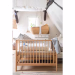 Livipur Livipur Beistellbett Ola aus Bio Erlenholz_2771 Ein gemütliches Kinderzimmer mit dem Livipur Beistellbett Ola aus Bio Erlenholz von Livipur im Vordergrund einem Sofa mit Kissen und einer hängenden Korbwiege am Fenster. Der Raum hat schräge Decken mit sichtbaren Balken und sanftes natürliches Licht.