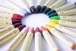 Ein Kreis von STOCKMAR Wachsmalstiften Einzelstift in 32 Farben von Stockmar die mit der Spitze nach innen angeordnet sind zeigt ein Spektrum von Rot Rosa und Orange bis hin zu Blau Grün und Braun; jeder Stift ist auf seiner Verpackung mit "Stockmar" besch indigo