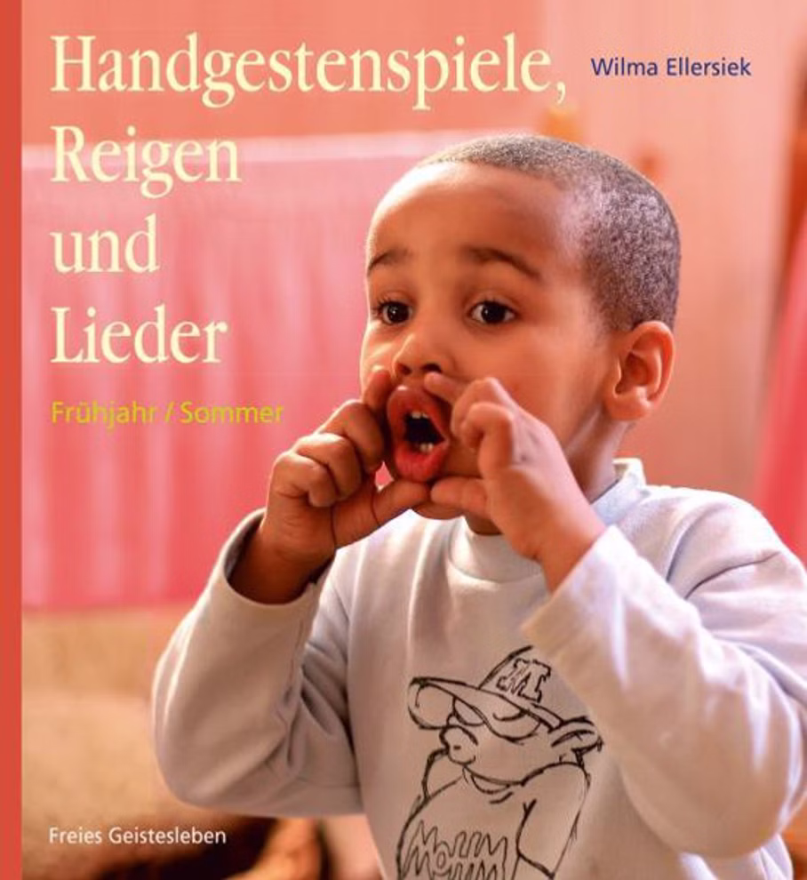 Freies Geistesleben Handgestenspiele Reigen und Lieder für Kindergarten und erstes Schuljahr Wilma Ellersiek_7811 Ein kleiner Junge mit kurzen Haaren gestikuliert spielerisch mit den Händen vor dem Mund. Das Buchcover zeigt "Handgestenspiele Reigen und Lieder für Kindergarten und erstes Schuljahr" von Wilma Ellersiek von Freies Geistesleben. Warmer Innenhintergrund.