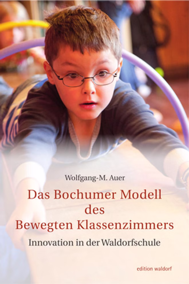 Pädagogische Forschungsstelle beim Bund der Freien Waldorfschulen e. V. Das Bochumer Modell des bewegten Klassenzimmers Innovation in der Waldorfschule_11499 Ein Junge mit Brille und rotem Hemd beugt sich über einen Tisch und liest konzentriert. Er liest gerade "Das Bochumer Modell des bewegten Klassenzimmers Innovation in der Waldorfschule" von der Pädagogischen Forschungsstelle beim Bund der Freien Waldorfsch