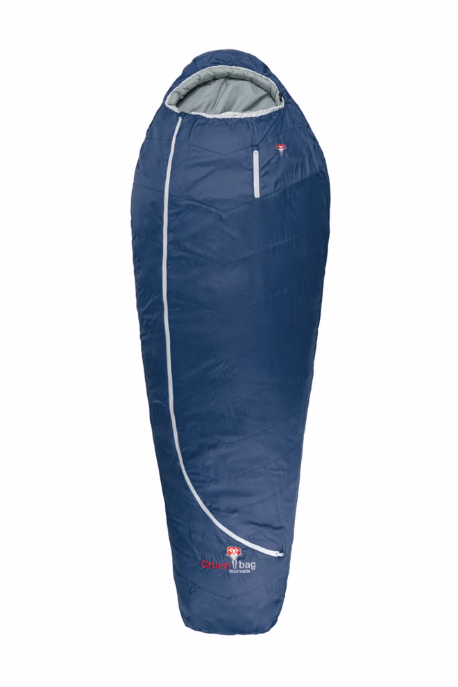 Schlafsack mit Almwolle Ein blauer Grüezi Schlafsack mit Almwolle für bis zu 185 cm Körpergröße im Mumien-Stil mit Kapuze hellgrauem diagonalem Reißverschluss von links oben nach rechts und Crux 1-Logo in der Nähe der unteren Vorderseite.