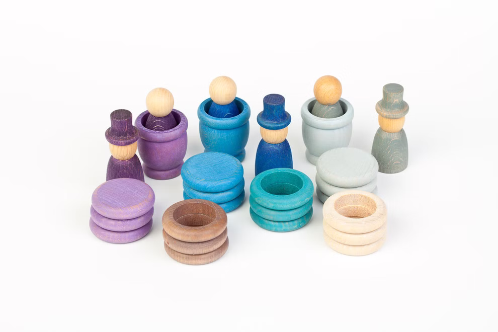 Grapat Grapat Holzspielzeug Winter Set _19622 Das Grapat Holzspielzeug Winter Set von Grapat besteht aus bunten Holzpuppen mit Hüten und Ringen in Blau Lila und natürlichen Holztönen. Das Set enthält Figuren und passende Kreisteile die alle auf einem weißen Hintergrund angeordnet sind.