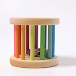 Der Grimm's Regenbogen Babyroller Ø 15 cm von Grimm's besteht aus zwei runden Holzsockeln die durch mehrfarbige vertikale Stäbe verbunden sind mit bunten Holzkugeln und einer Metallglocke im Inneren. Das Spielzeug ist vor einem schlichten weißen Hintergrun