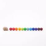 Eine Grimm's 60 Holzperlen Ø 2 cm liegt in einer Reihe von zwölf regenbogenfarbenen Grimm's Perlen die in einer geraden Linie auf weißem Grund angeordnet sind.