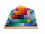 Grimm's Kleine Stufenpyramide von Grimm's zeigt bunte Holzwürfel die in einer Pyramide auf einem Holztablett angeordnet sind wobei jede Schicht unterschiedliche Farben von Grün an den Rändern bis Gelb Orange und Rot in der Mitte aufweist.