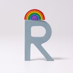 Ein hellblauer Holzbuchstabe R aus Grimm's Buchstaben aus Holz A-Z von Grimm's steht aufrecht mit einer kleinen bunten Regenbogenverzierung auf der Spitze vor einem schlichten weißen Hintergrund. R