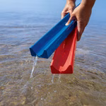 Zwei Hände halten die Wasser- und Murmelstraße 5 Spuren Rinnen von ERZI im flachen Wasser und lassen das Wasser durch die V-förmigen Rillen fließen während sie von der Oberfläche gehoben werden.