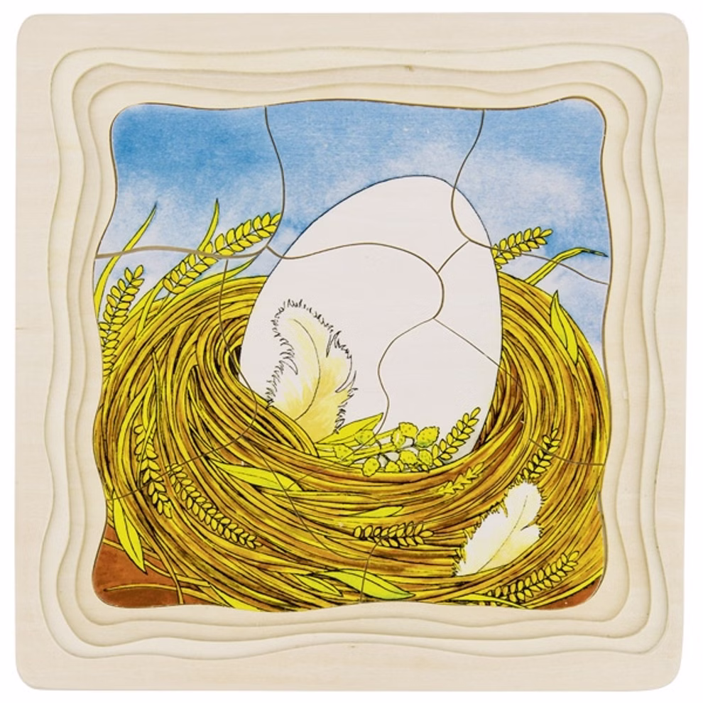 Goki Schichtenpuzzle Das Huhn _23565 Das Goki Schichtenpuzzle Das Huhn ist ein Holzpuzzle mit der Illustration eines großen weißen Eies in einem gelben Nest mit Federn und Weizen vor einem blauen Himmelshintergrund.