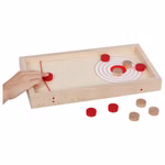 Eine Hand wirft einen roten Puck auf das Goki Super Puck Brettspiel 2 in 1 Holzspielbrett und zielt auf ein Ziel mit konzentrischen Kreisen. Mehrere rote und natürliche Pucks sind auf und um das Brett herum verstreut.