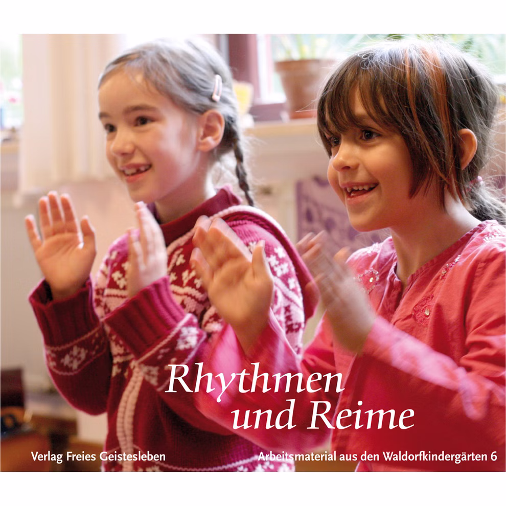 Freies Geistesleben Rhythmen und Reime Freya Jaffke_2346 Zwei junge Mädchen in Pullovern lächeln und klatschen in einem Haus in die Hände. Das Bild zeigt den Text "Rhythmen und Reime Freya Jaffke" mit den Verlags- und Serieninformationen von Freies Geistesleben darunter in Deutsch.