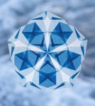 Die Leuchtende Fenstersterne Frédérique Guéret von Freies Geistesleben zeigt ein geometrisches blau-weißes Schneeflockenmuster mit sich überlappenden Dreiecken und Rauten auf einem weichen verschwommenen blauen Hintergrund.