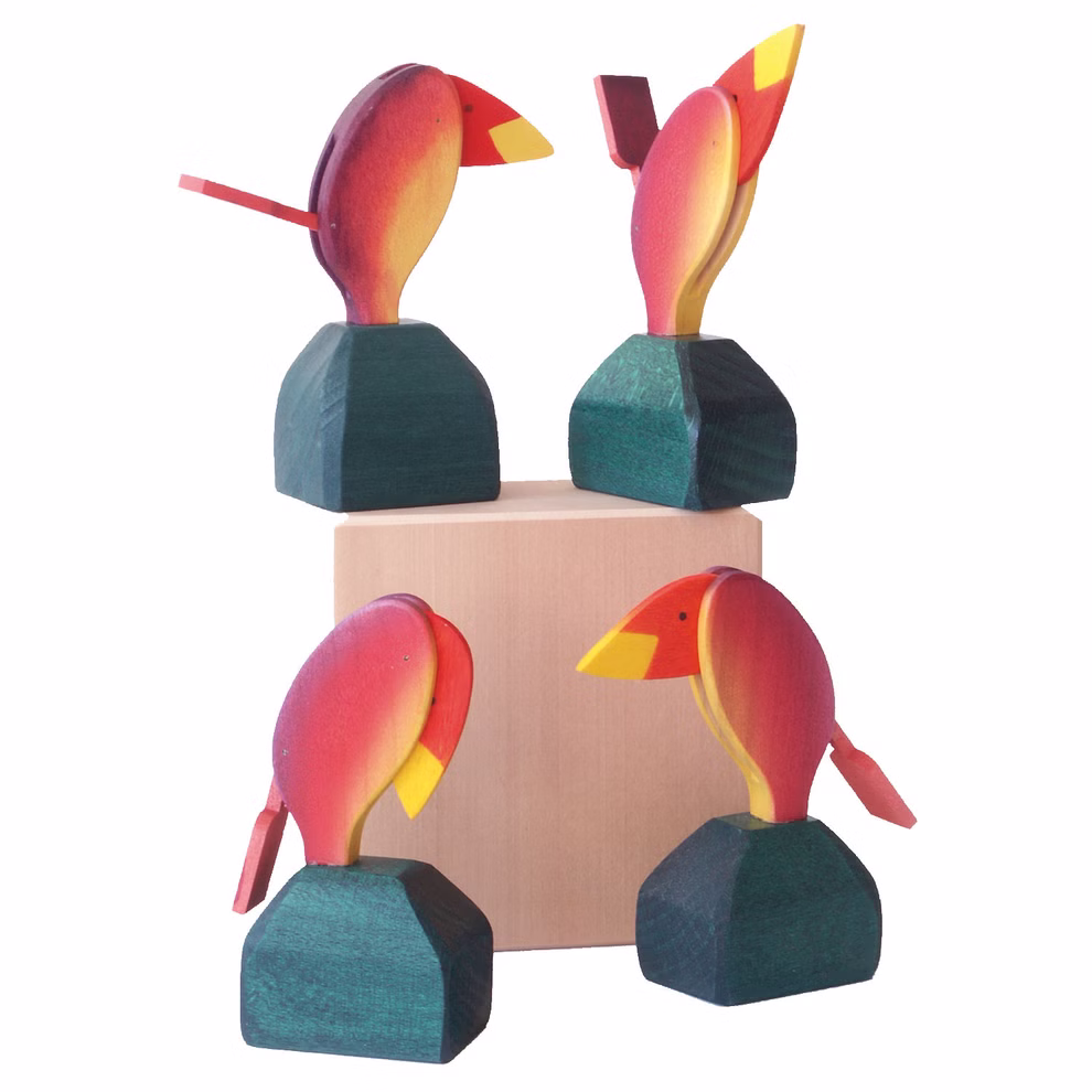 Decor Stimmungsvogel Temperamentsvogel _315 Vier farbenfrohe Decor Stimmungsvogel Temperamentsvogel Holztukanfiguren mit roten gelben und grünen Akzenten sind um einen hellen Holzblock herum angeordnet wobei jede Figur anders positioniert ist um einzigartige Winkel und Flügelstellungen hervorzuheben