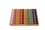 Das Romanswerk Farbenspiel 10x10 besteht aus einem Holztablett mit 100 bunten Filzkugeln die in einem Raster angeordnet und nach den Farben Weiß Rosa Orange Gelb Grün Türkis Blau und Marine geordnet sind.