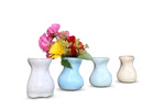 Das Lautenbach-Set "Vase in vier Farben" besteht aus vier kleinen Keramikvasen drei leeren und einer gefüllten mit leuchtend rosafarbenen gelben und roten Blumen die alle vor einem sanft verschwommenen Holzhintergrund angeordnet sind. gelb pastell