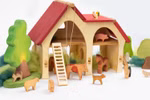 Das Decor Bauernhaus (30 x 33 x 15 cm) ist eine hölzerne Spielzeugscheune mit rotem Dach umgeben von hölzernen Kühen Pferden Schweinen Hunden Schafsfiguren Filzbäumen und Sträuchern und mit einer Leiter die an die Scheune gelehnt ist.