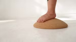 Ein nackter Fuß drückt auf das kuppelförmige Balancepad der.Wackler aus Kork von TicToys das auf einem weißen Boden vor einem schlichten weißen Hintergrund liegt.