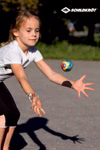 Schildkröt High Bounce Balls (Flummies) 3-er Set _26508 Ein junges Mädchen in einem weißen T-Shirt steht im Freien und fängt einen bunten High Bounce Ball (Flummie) aus dem 3-teiligen Set von Schildkröt. Das Schildkröt-Logo erscheint in der oberen rechten Ecke des Bildes.
