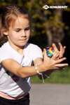 Schildkröt High Bounce Balls (Flummies) 3-er Set _26509 Ein junges Mädchen in einem weißen T-Shirt fokussiert sich während sie einen bunten Schildkröt High Bounce Ball (Flummies) aus dem 3-er Set im Freien fängt wobei das Sonnenlicht ihr Gesicht und ihre Hände beleuchtet. Das Schildkröt-Logo ist in der oberen r