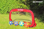 Schildkröt Fußballtore Pop-Up mit Aufbewahrungstasche _26496 Ein Schildkröt Fußballtore Pop-Up mit Aufbewahrungstasche dargestellt auf grünem Rasen mit vier bunten Fußbällen davor und Büschen dahinter. Das Schildkröt-Logo ist in der oberen rechten Ecke zu sehen.