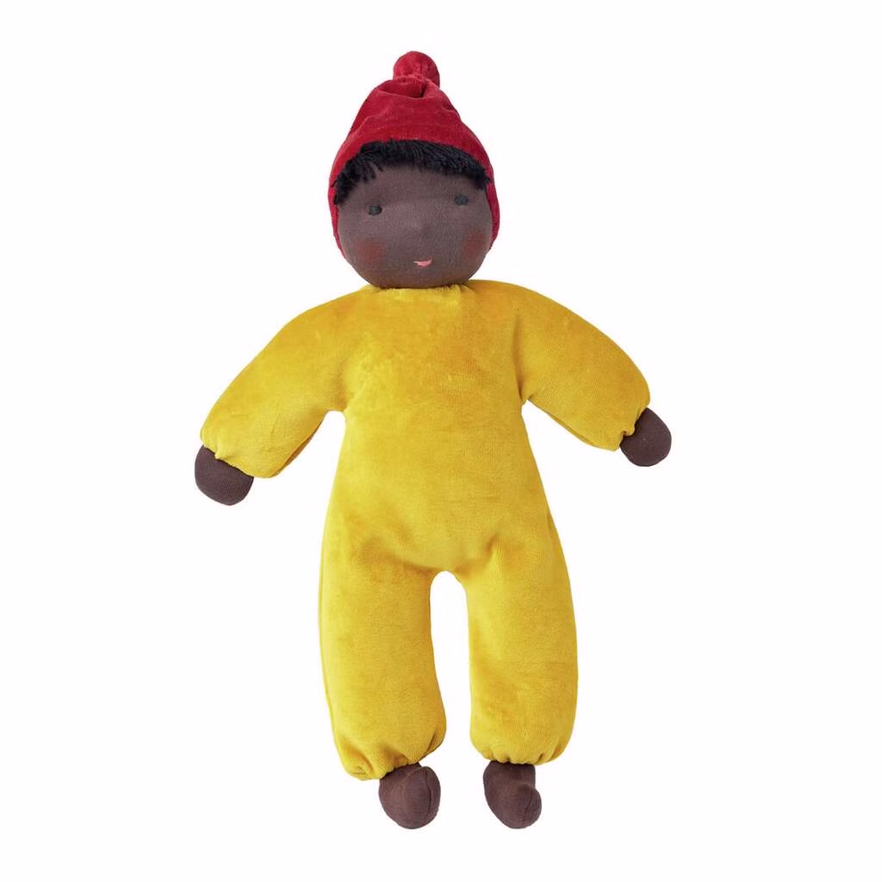 Käthe Kruse Waldorfpuppe Nana safran 35 cm_26613 Die Käthe Kruse Waldorfpuppe Nana safran 35 cm ist eine weiche Plüschpuppe mit dunkelbrauner Haut schwarzen Haaren einem roten Hut und einem gelben Einteiler. Sie hat einfache Gesichtszüge und schlaffe Arme und Beine.
