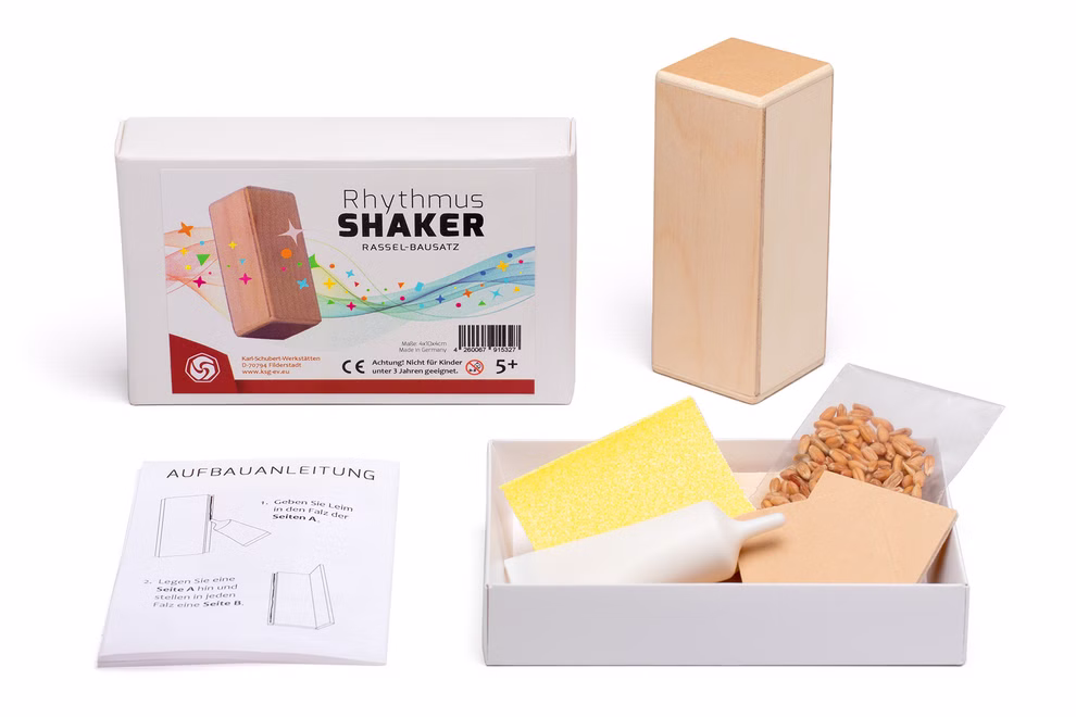 Karl Schubert Gemeinschaft Bausatz Rhythmus Shaker Klangspielzeug_29971 Der Bausatz Rhythmus Shaker Klangspielzeug von Karl Schubert Gemeinschaft enthält einen Holzblock eine Anleitung kleine Bohnen einen Schwamm Sandpapier einen Plastiktrichter und wird in einer Schachtel mit der Aufschrift Rhythmus Shaker geliefert.
