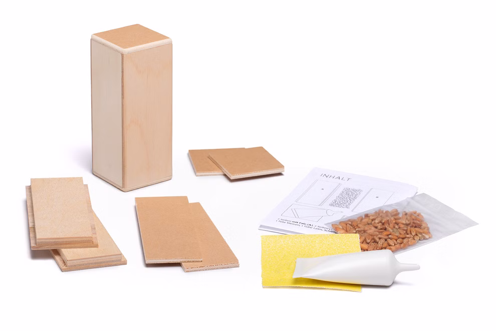 Karl Schubert Gemeinschaft Bausatz Rhythmus Shaker Klangspielzeug_29972 Der Bausatz Rhythmus Shaker Klangspielzeug von Karl Schubert Gemeinschaft enthält Holzplatten Schleifpapier eine Leimtube Nägel und eine Anleitung alles auf einer weißen Fläche.