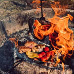 Mit dem Stabilotherm Lagerfeuer Grilleisen können Sie Würstchen Hähnchen Kirschtomaten und gelbe Paprika über heißen Kohlen zubereiten wobei die Flammen um Ihr Essen herum aufsteigen.