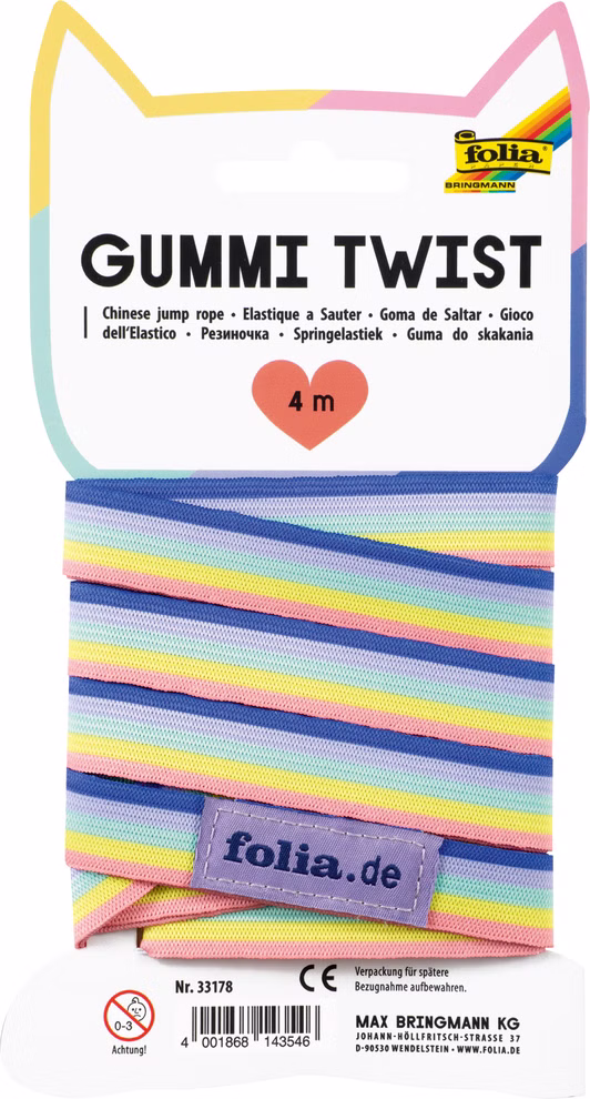 Folia Gummi-Twist Regenbogen 4m_33087 Das Folia Gummi-Twist Regenbogen 4m ist ein bunt gestreiftes elastisches Springseil verpackt in einem gefalteten Katzenohren-Display mit mehrsprachigem Text.