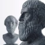 Nahaufnahme des Platonischen Körpers Bergkristall ø 2 cm von Marco Schreier Mineralienhandlung GmbH mit einer anderen ähnlichen Kristallform unscharf im Hintergrund vor einem weißen Hintergrund.