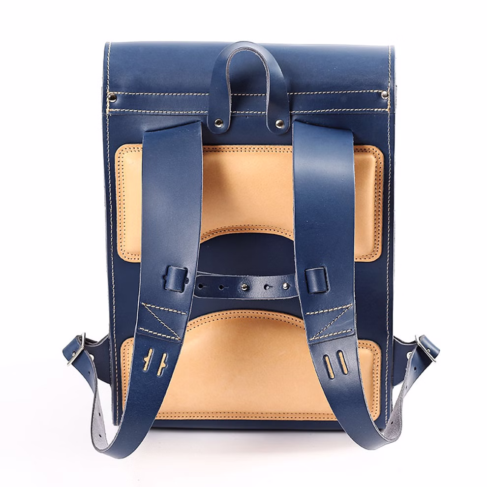 hukkepack Schulranzen Leder Blau Kompakt _32596 Der hukkepack Schulranzen Leder Blau Kompakt ist ein marineblauer und hellbrauner Lederrucksack mit verstellbaren Trägern sichtbaren Nähten und einem Tragegriff oben. Sein robustes Design verbindet Stil mit Funktionalität.